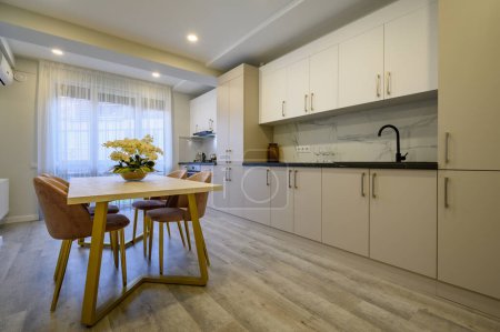 Foto de Interior de una amplia cocina de lujo de color beige y crema con mesa de comedor - Imagen libre de derechos