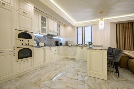 Foto de Cream-colored classic kitchen with island serving as dining area in studio apartment interior - Imagen libre de derechos
