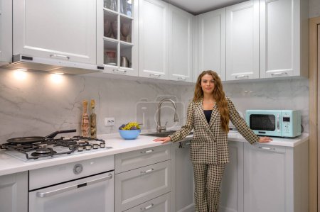 Téléchargez les photos : Portrait de jeune femme au foyer mignonne dans l'intérieur de la cuisine à l'arrière-plan - en image libre de droit