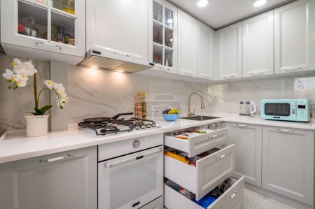 Foto de Primer plano de la nueva encimera de cocina moderna blanca y gris bien diseñada, algunos cajones sacados - Imagen libre de derechos