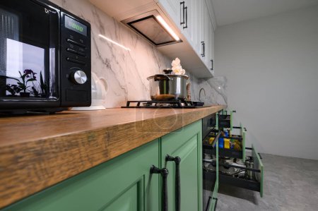 Téléchargez les photos : Green and white colored modern kitchen details, closeup to furniture details with microwave - en image libre de droit