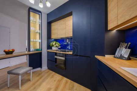 Téléchargez les photos : Stylish large blue and wood colored studio apartment with kitchen open to living room after good renovation - en image libre de droit
