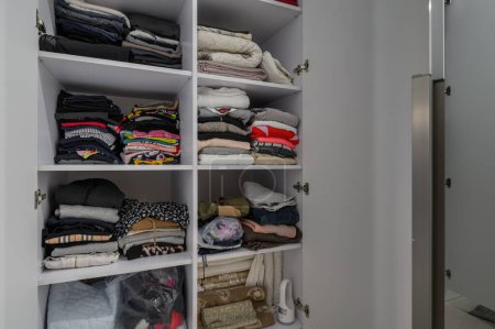 Photo for Open big white wardrobe with different clothes at shelves - Royalty Free Image