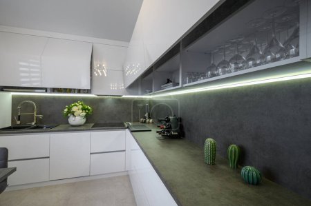 Foto de Closeup to dark grey stone counter work top at white trendy kitchen - Imagen libre de derechos