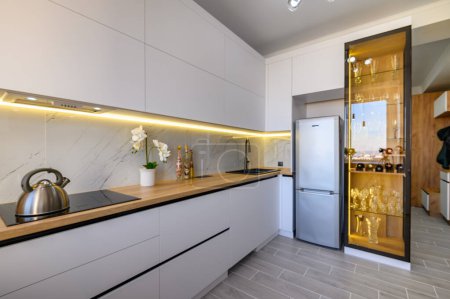 Téléchargez les photos : A chic white studio apartment with a fully equipped kitchen and a sleek glass sideboard - en image libre de droit