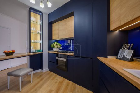 Téléchargez les photos : Stylish large blue and wood colored studio apartment with kitchen open to living room after good renovation - en image libre de droit