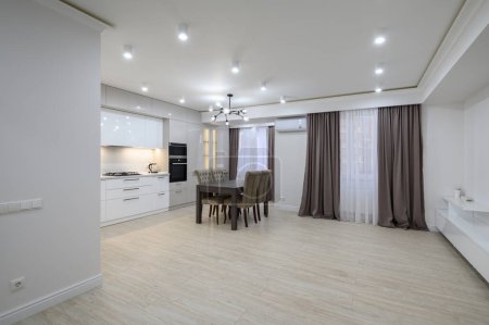 Photo for Large modern new well designed white kitchen interior after renovation in studio apartment, panoramic windows covered with curtains, plenty of copy space - Royalty Free Image