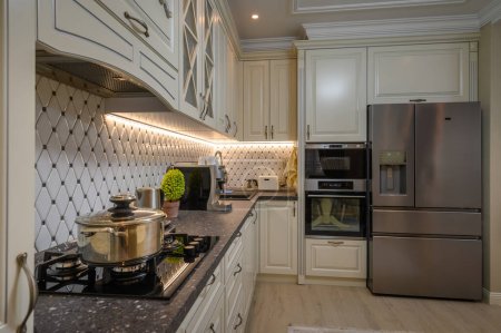 Téléchargez les photos : Élégante cuisine ouverte avec une palette de couleurs beige et des éléments de design classiques, à proximité du plan de travail - en image libre de droit