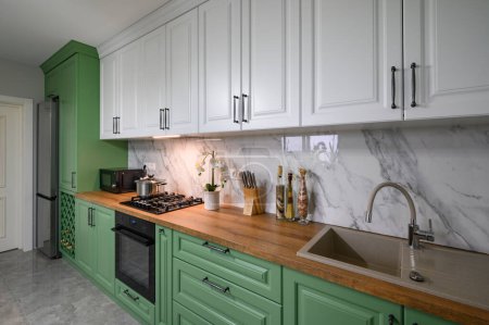 Foto de Green and white colored modern kitchen details, closeup to wooden counter - Imagen libre de derechos