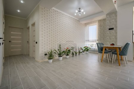 Téléchargez les photos : Modern trendy white studio apartment with a dining table and row of green plants, lot of copy space - en image libre de droit