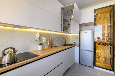 Téléchargez les photos : A trendy white studio with a functional kitchen and a chic glass sideboard, closeup to worktop - en image libre de droit