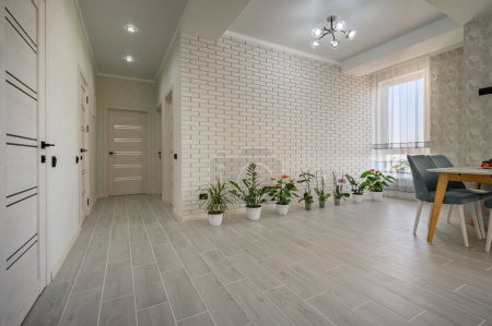 Téléchargez les photos : Modern fashionable white studio apartment with a dining table and row of green plants, lot of copy space - en image libre de droit