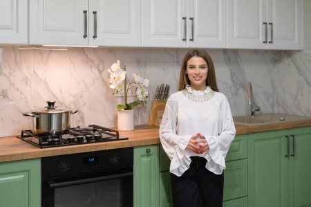 Téléchargez les photos : Young cute woman at new green colored modern well designed kitchen interior after renovation - en image libre de droit