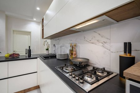 Téléchargez les photos : Détails de cuisine moderne de luxe blanc et noir, gros plan de travail avec cuisinière à gaz et autres appareils - en image libre de droit