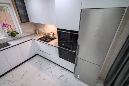 Foto de Una cocina espaciosa y actualizada con esquema de color blanco y negro, con estantes extraíbles para un almacenamiento y organización convenientes, vista de ángulo alto - Imagen libre de derechos