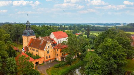 Castillo medieval de Lielstraupe en el pueblo de Straupe en Vidzeme, en el norte de Letonia. Aerial Dron Shot Lielstraupe Castle United in One Corps With the Church Rodeado por un parque con estanque.