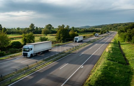 Foto de Convoy de camiones blancos con contenedores en carretera, concepto de transporte de carga en primavera - servicio de carga - Imagen libre de derechos