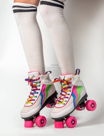 Foto de Retrato de piernas de mujer con patines de cuatro ruedas con cordones de colores sobre fondo blanco - Imagen libre de derechos