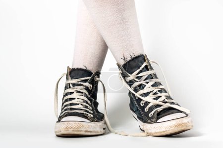 Foto de Viejas zapatillas azules estilo hipster en piernas de niña en sobre los calcetines de rodilla, sobre un fondo blanco - Imagen libre de derechos