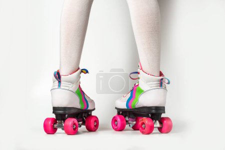 Retrato de piernas de mujer con patines de cuatro ruedas con cordones de colores sobre fondo blanco