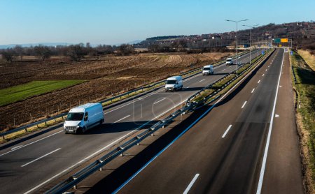 Vier Lieferwagen stehen auf einer Autobahn Schlange. Kleintransporter auf einer Straße