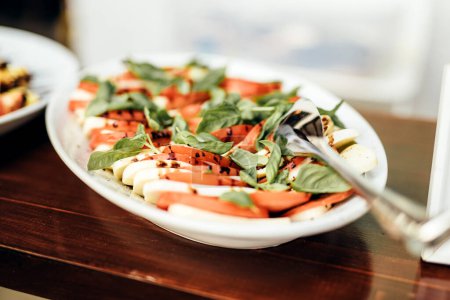 Foto de Tomate y mozzarella con hojas de albahaca - Imagen libre de derechos