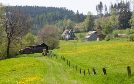 countryside landscape near winterberg in german sauerland with houses, farm and spring flowers