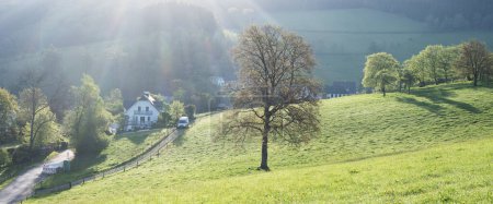 frische Laubbäume und Felder in Dorfnähe in schöner sauerländischer Landschaft im Frühling in Deutschland