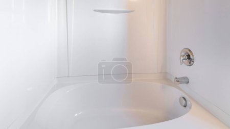 Téléchargez les photos : Panorama Kit combo baignoire-douche en alcôve avec pomme de douche murale et robinet. Salle de bain intérieure avec baignoire murale acrylique surround contre le mur beige. - en image libre de droit