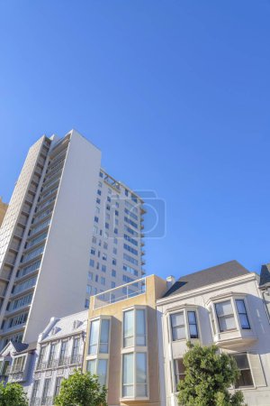 Photo for Low-rise flat apartments near the mid-rise apartment in San Francisco, CA. There are low-rise buildings at the front with different exterior and a view of taller building with picture windows. - Royalty Free Image