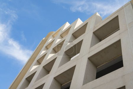 Foto de Vista de bajo ángulo de un edificio abierto con ventanas cuadradas bajo el cielo en Miami, Florida. Edificio beige pintado con vista de la estructura del techo en capas desde abajo. - Imagen libre de derechos