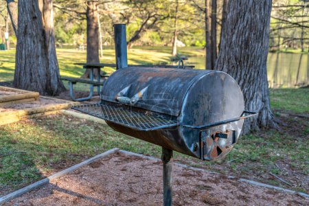 Photo for An old rusty barbeque grill at a park for hikers in Bull Creek Austin Texas. Close up view of a weathered outdoor cooking equipment at a picnic are amid big trees on a sunny day. - Royalty Free Image