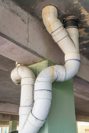 Foto de Destin, Florida- Blanco tuberías de desagüe de PVC vista desde abajo en un garaje de estacionamiento. Escurrir tuberías cerca de las columnas de hormigón a través del techo de hormigón. - Imagen libre de derechos