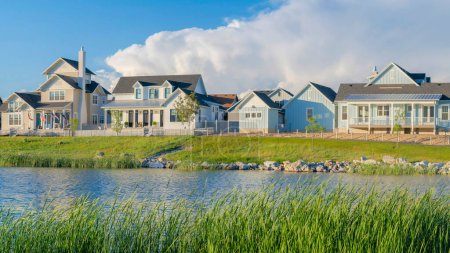 Photo for Panorama White puffy clouds Panoramic view of blue waters of Oquirrh Lake at Daybreak in South Jordan, California. Residential area with lake waterfront with tall grasses at the front. - Royalty Free Image