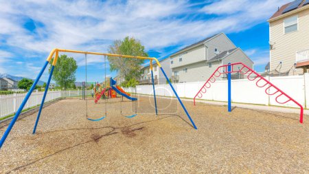 Photo for Panorama Whispy white clouds Small community playground near the fenced residential houses at Utah Valley. There are colorful playground equipments inside the picket fence against the view of houses and mountains at the back. - Royalty Free Image