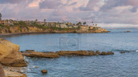 Téléchargez les photos : Panorama Nuages gonflés au coucher du soleil Zone côtière de La Jolla en Californie avec vue sur l'océan Pacifique. Rivage rocheux d'un océan avec vue sur les bâtiments résidentiels à gauche et océan en bord de mer à droite. - en image libre de droit