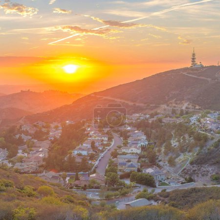 Téléchargez les photos : Square Coucher de soleil spectaculaire avec nuages Vue panoramique d'un quartier résidentiel à flanc de montagne dans le comté de San Diego en Californie. Vue du dessus d'une communauté contre la vue de l'horizon du coucher du soleil. - en image libre de droit
