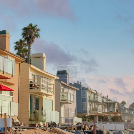Foto de Square Nubes hinchadas al atardecer Fila de edificios de casas de playa con tumbonas afuera en Oceanside, California. Edificios con diferentes diseños y estilo con barandillas de vidrio en cubiertas y balcones. - Imagen libre de derechos