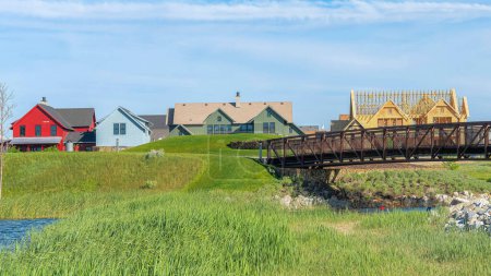 Photo for Panorama Whispy white clouds Arched bridge over the Oquirrh Lake at Daybreak, Utah. There is a green field on a hill against the colorful houses on the back and an unfinished house with woodframes at the back of the bridge. - Royalty Free Image
