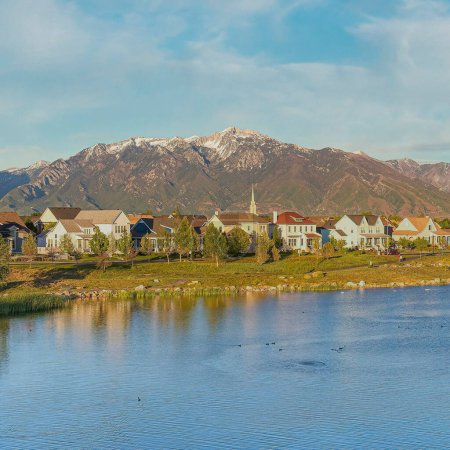 Photo for Square Whispy white clouds Top view of Oquirrh Lake in a residential area at Daybreak, Utah. There are walkways surrounding the lake at the front of th houses against the view of the mountain range at the background. - Royalty Free Image
