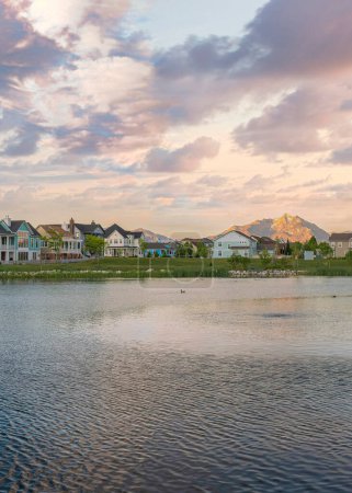 Photo for Vertical Puffy clouds at sunset Panoramic view of Oquirrh Lake with reflective water at Daybreak, Utah. There are large residential buildings and mountains on the right at the back. - Royalty Free Image