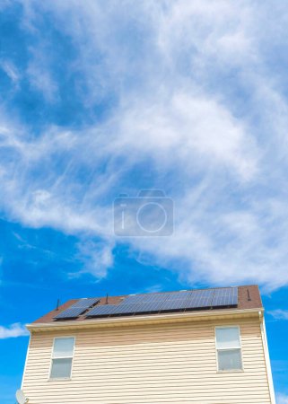 Foto de Nubes blancas Vertical Whispy Vista de ángulo bajo de dos casas con paredes de vinilo de madera y paneles solares en el techo en el valle de Utah. Hay una casa beige a la izquierda junto a la casa gris a la derecha contra el cielo al fondo. - Imagen libre de derechos