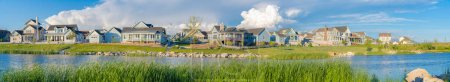 Photo for Panoramic view of blue waters of Oquirrh Lake at Daybreak in South Jordan, California. Residential area with lake waterfront with tall grasses at the front. - Royalty Free Image