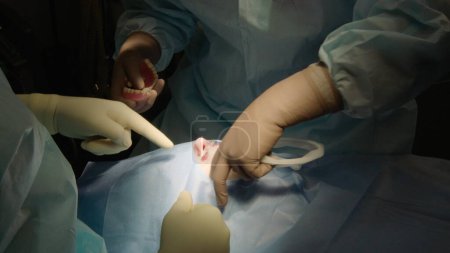 Foto de Un primer plano de un cirujano dental que realiza una operación de implante dental. En una clínica dental moderna. Los dentistas examinan la cavidad oral del paciente antes de la cirugía. El trabajo de los médicos en el quirófano - Imagen libre de derechos