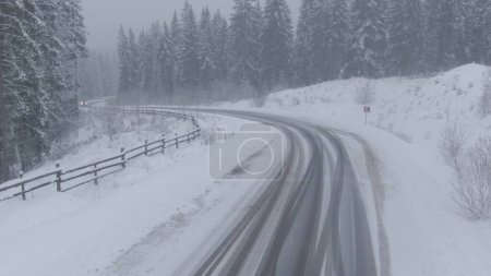 Photo for Top view from a drone of a car driving on a snowy icy road in a blizzard bird's eye view of the car. - Royalty Free Image