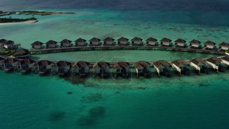 Foto de Vista aérea de villas de lujo sobre el agua en la laguna azul, playa de arena blanca. Una isla con bungalows sobre el agua en hileras en las Maldivas. - Imagen libre de derechos