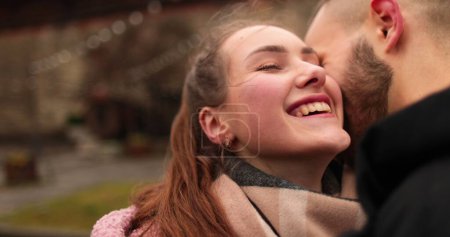 Foto de Primer plano de las caras de una joven pareja enamorada besándose y abrazándose en la calle en un sombrío día de otoño. - Imagen libre de derechos