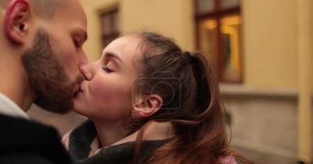 Foto de Primer plano de las caras de una joven pareja enamorada besándose y abrazándose en la calle en un sombrío día de otoño. - Imagen libre de derechos