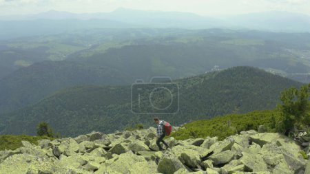 Foto de Un hombre camina a lo largo de una ladera cubierta de piedras gigantes. Turismo en solitario. Caminata dura, concepto de turismo de aventura. - Imagen libre de derechos