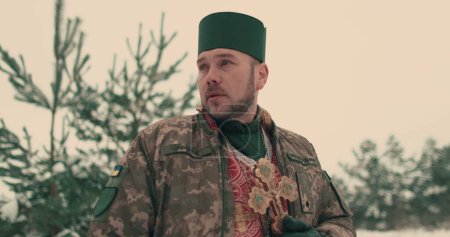 Kaplan in Militäruniform der ukrainischen Armee. Porträt eines jungen Kaplans in einem verschneiten, offenen Raum. Der Krieg der Ukraine mit Russland.